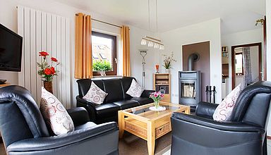 Ferienhaus Britschock - Wohnzimmer mit dunklen Möbeln und hellem Mobiliar
